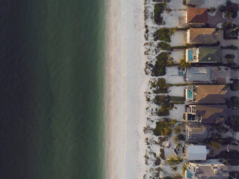 Aerial view of beachfront houses beside the ocean — stock illustration